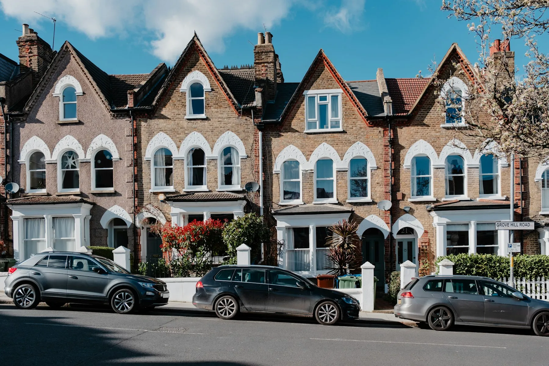 A row of brick terraced houses with parked cars on a residential street